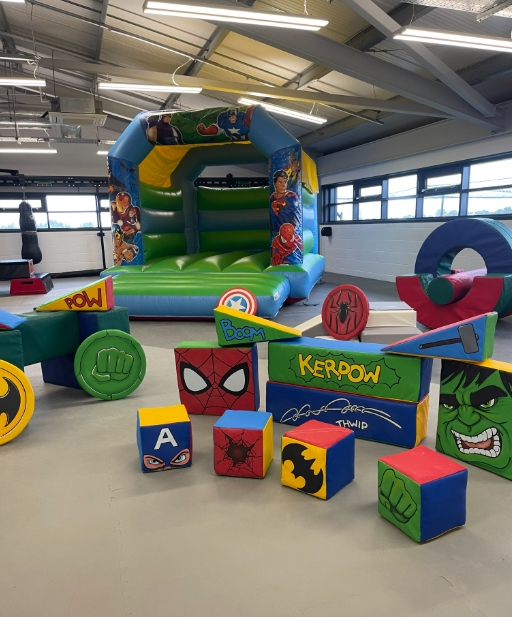 superhero-themed inflatable bounce house with colorful soft play blocks