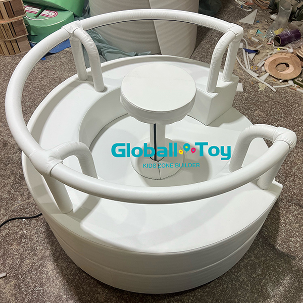 Indoor toddler spin toy with circular padded base for soft play zone installation