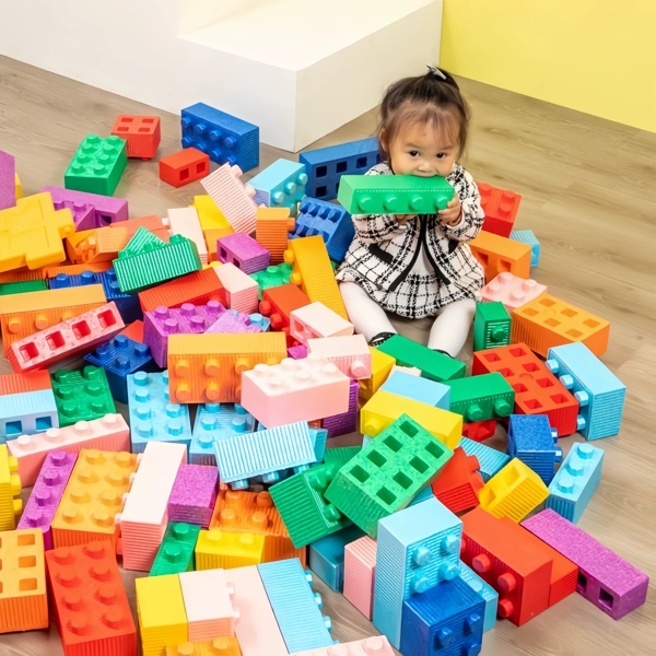 Toddler assis dans des blocs géants de jeu doux coloré pour l'aire de jeux intérieure et le centre de garderie